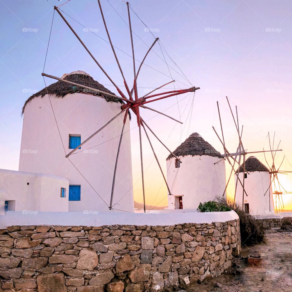 White mills on a greek island at sunset