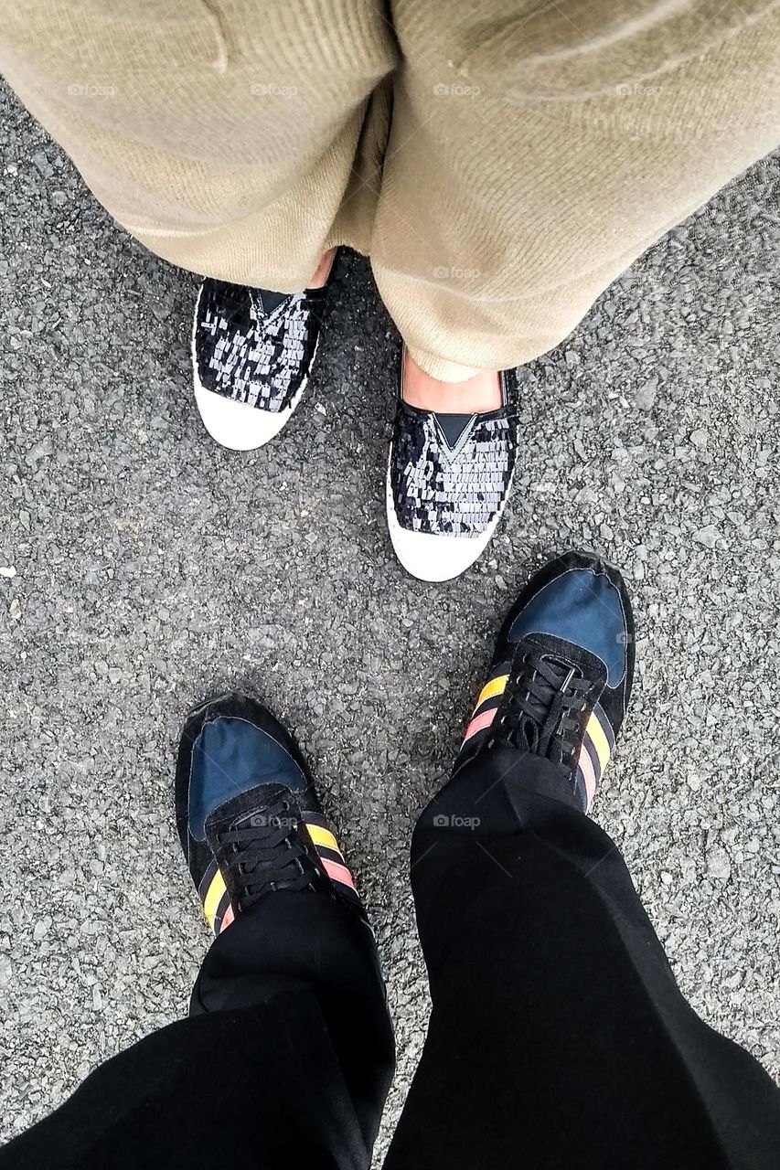 two people standing opposite each other, focusing on their shoes worn on the asphalt road surface