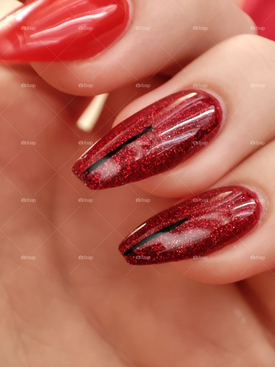 Gel nail manicure with red glittery polish/ Beautiful polish on nails/ Naturally long nails with gel nail polish/Red nails with a simple design up close
