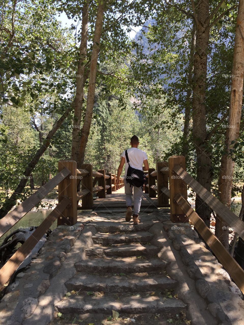 Man walks on a wooden bridge in the woods