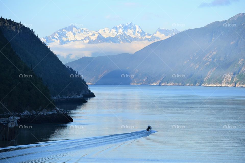 A small boat travels through an Alaskan fjord