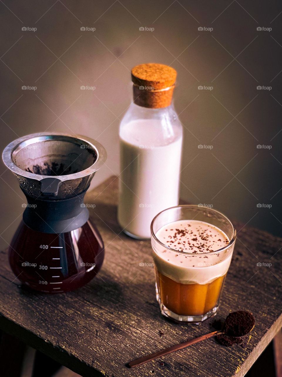 Cafe latte in a cup with coffee dripper at the side and a bottle of milk at the back view from top