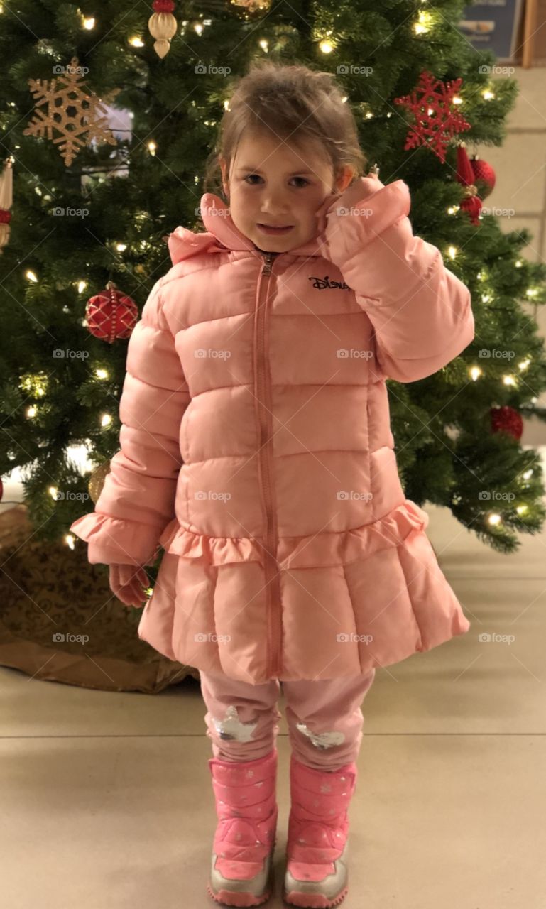 A Little Girl Standing in Front Of The Christmas Tree