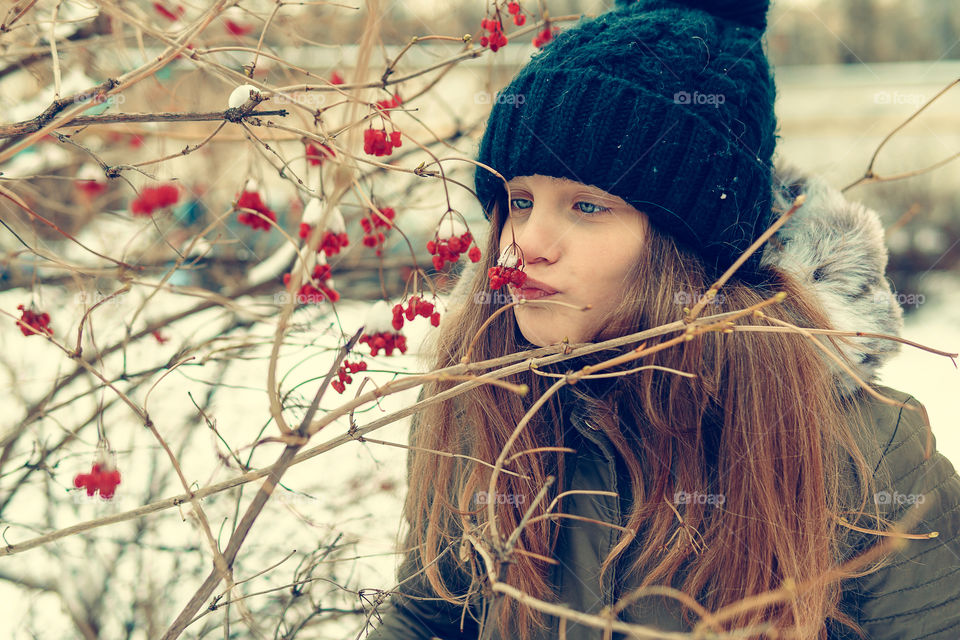 Girl is having fun and kissing winter berries covered with snow