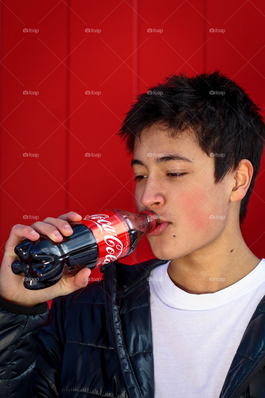 Teen boy is drinking Coca-Cola