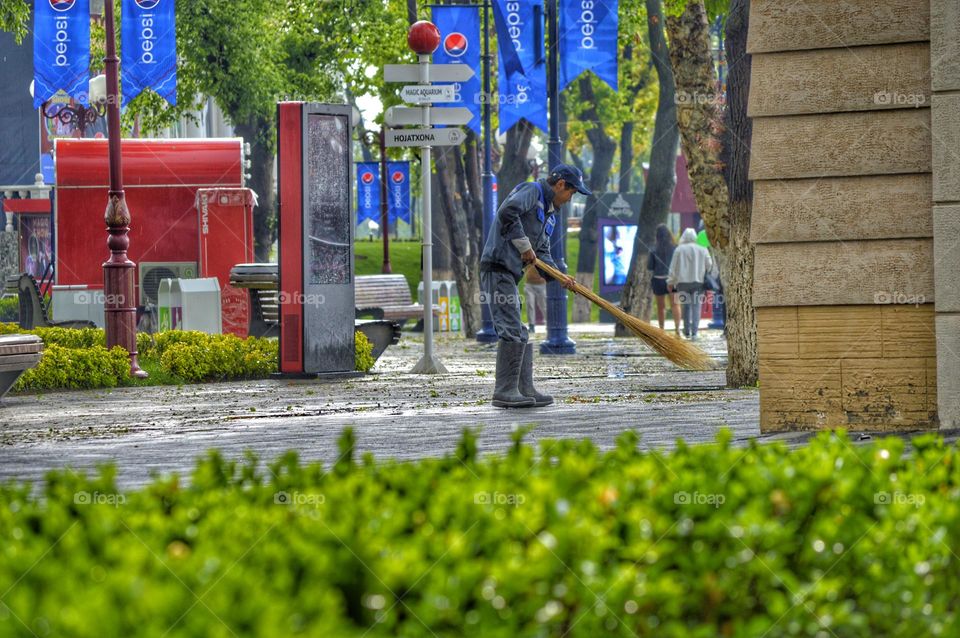 a man is sweeping the park with a large straw broom.