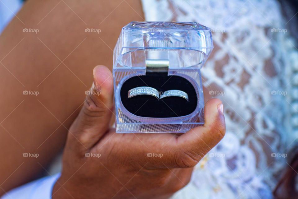 Man is holding a wedding ring box in his right hand.