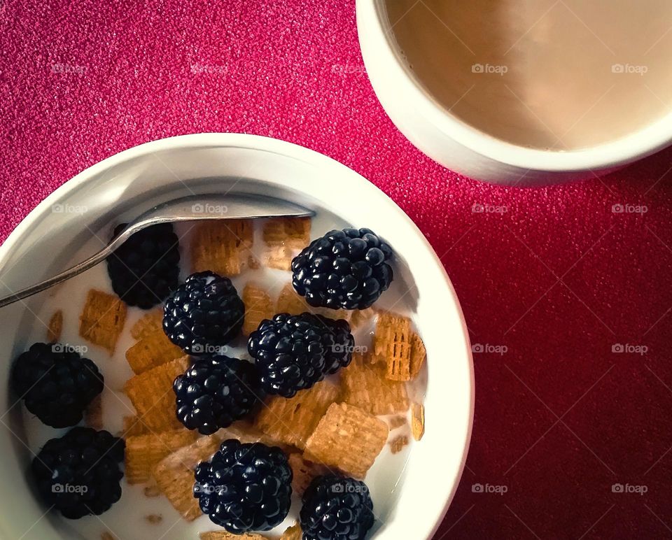 Cereal with Blackberries & coffee with cream breakfast on a magenta tablecloth