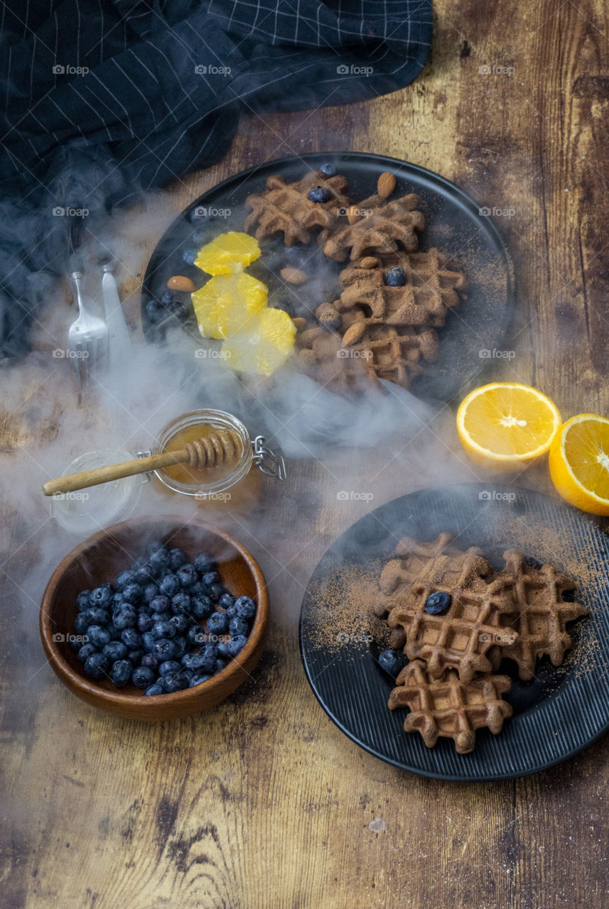 dessert of chocolate waffles with blueberries on a dark background