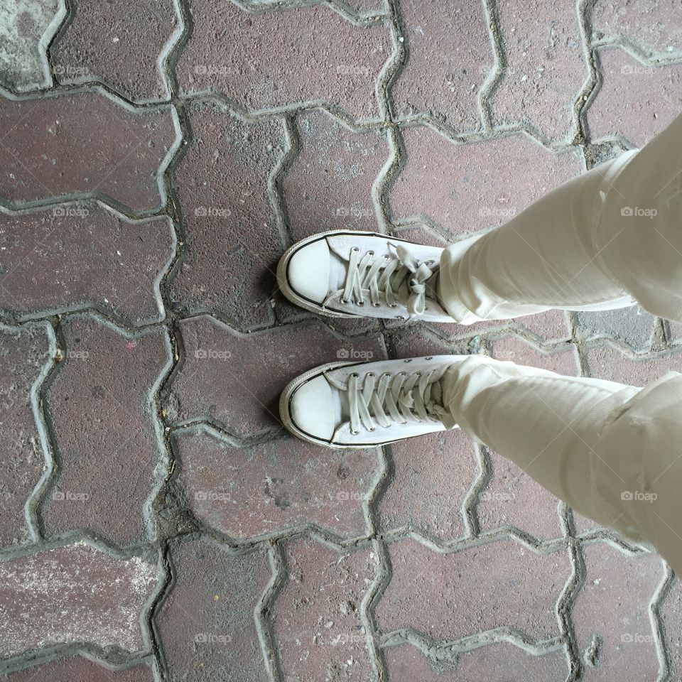 Close-up Picture of Woman Who Crossed Her Legs. Woman in Black Jeans and Sneakers Enjoying Daytime