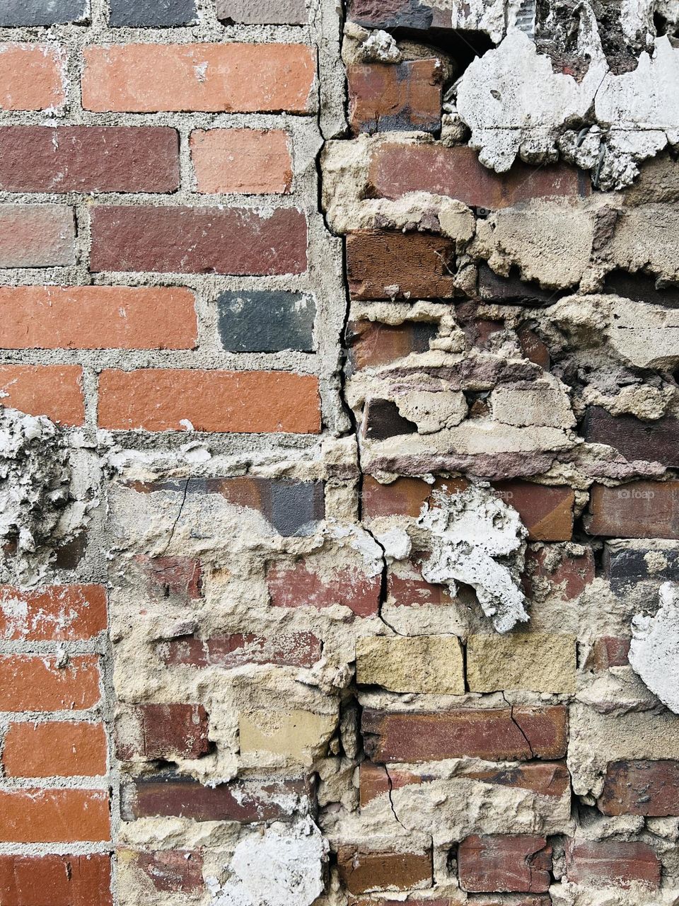 Brick wall closeup highlights crumbling mortar and repairs, but still standing. Persistence and strength in an abstract full frame.