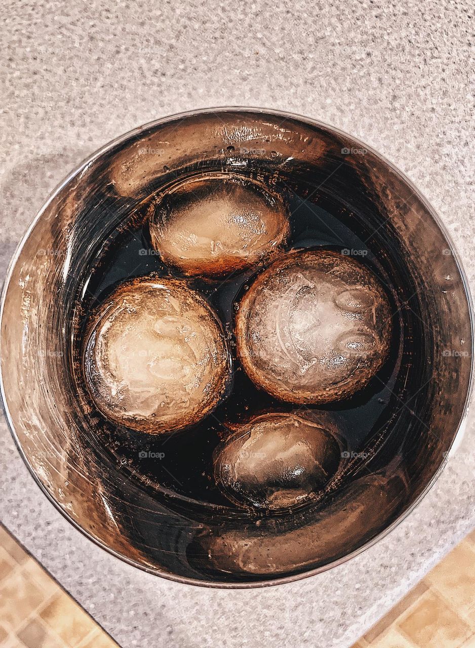 Cup with circular ice cubes in drink, drinking a soda from a cup, smiley face ice cubes in drink for fun, soda with smiley faces, drinking soda from a cup, smiley face circular ice cubes 