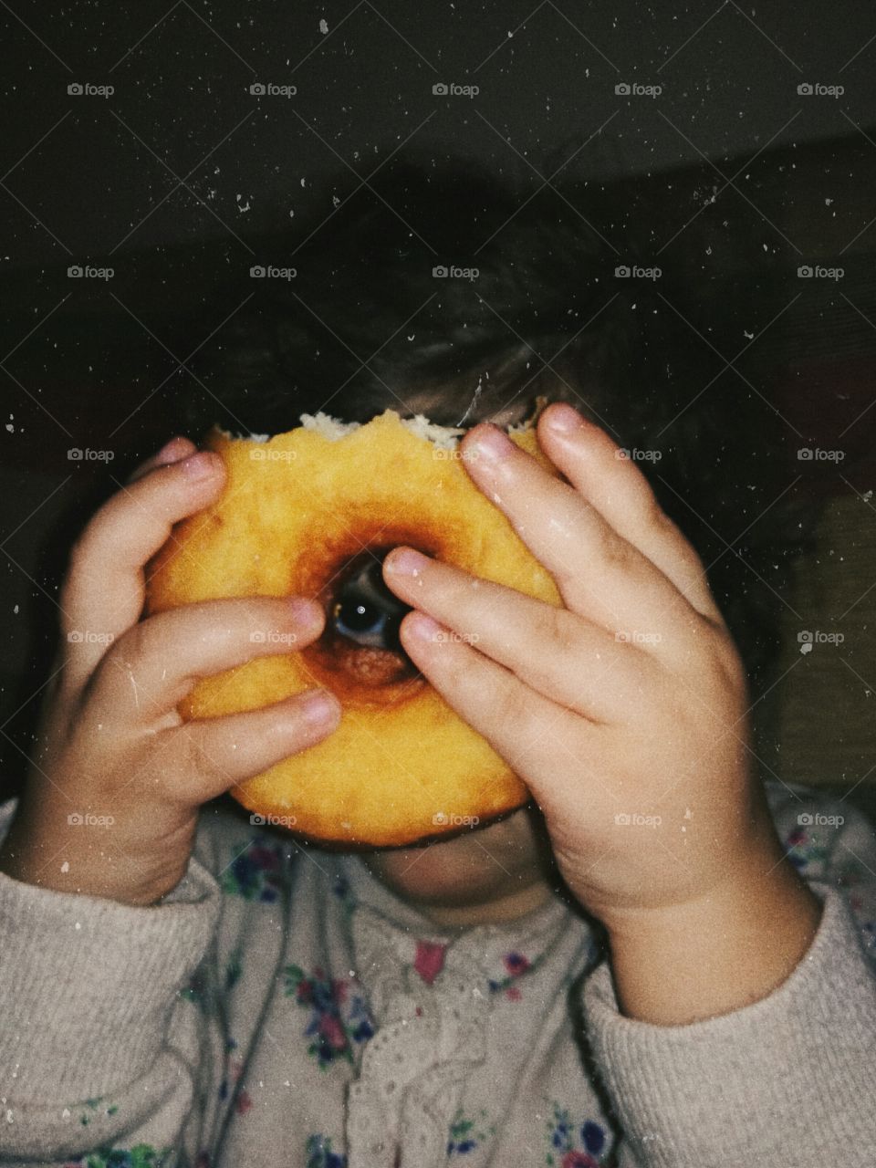 Baby girl looking through a hole in a donut