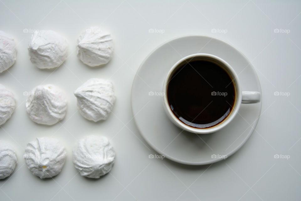 coffee mug and sweet sugar meringues on a white background top view