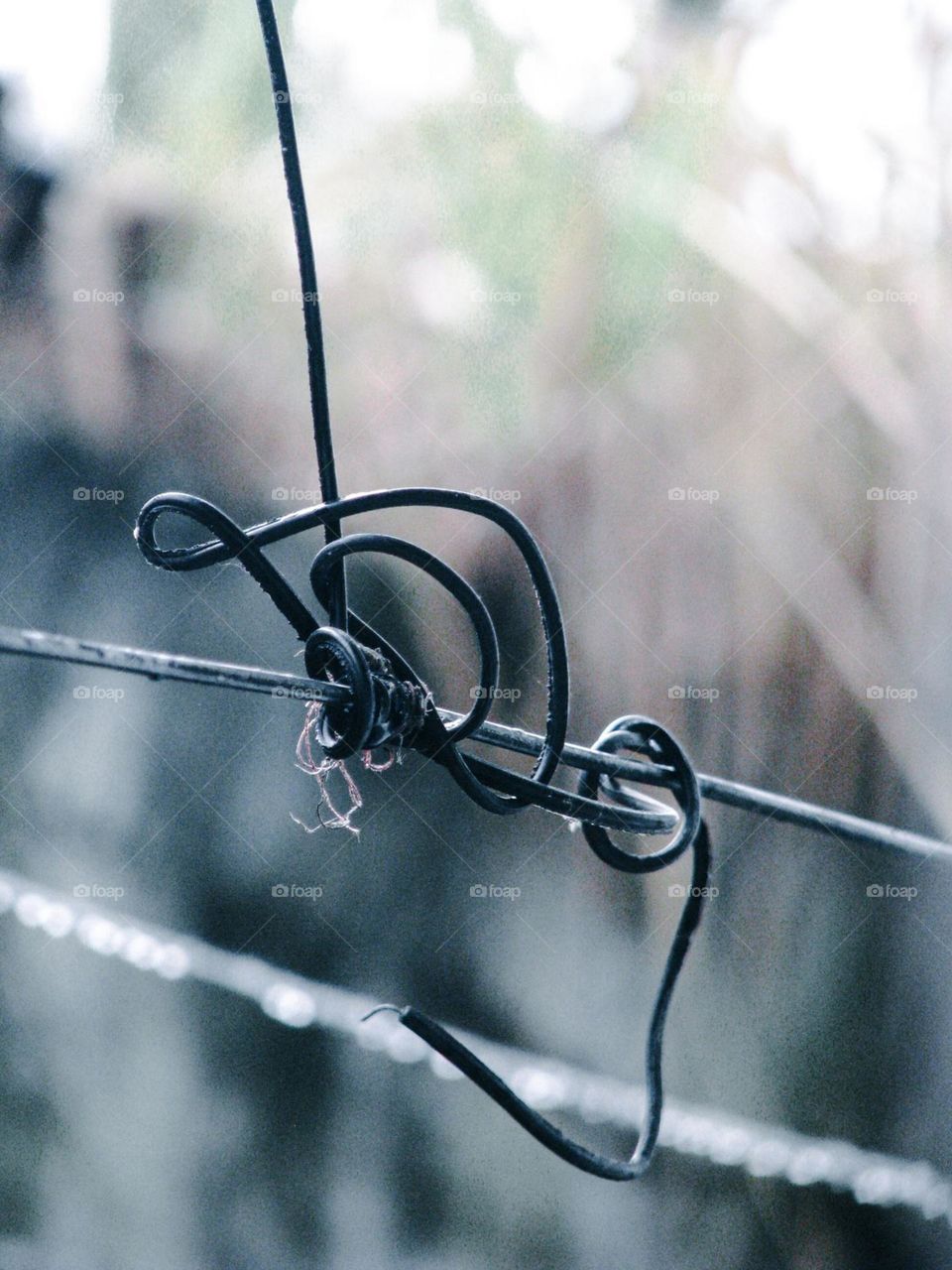 Close-up view of a piece of wire twisted and attached to another wire with a blurred background