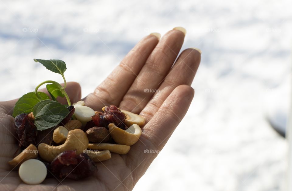 Holding healthy snack food nuts and berry mix outdoors in golden hour sunshine with dried blueberries, cranberries and cashew superfoods 