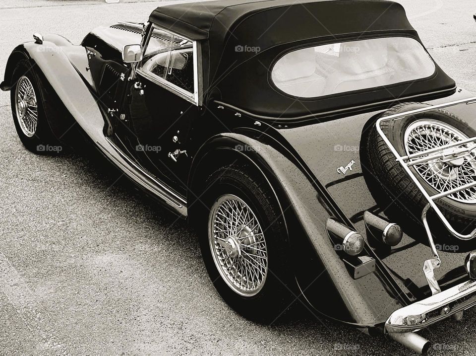 Sepia shot of a Morgan Convertible taken sideway showing the side and part of the back with spare tyre and rear lights at Cherbourg car show
