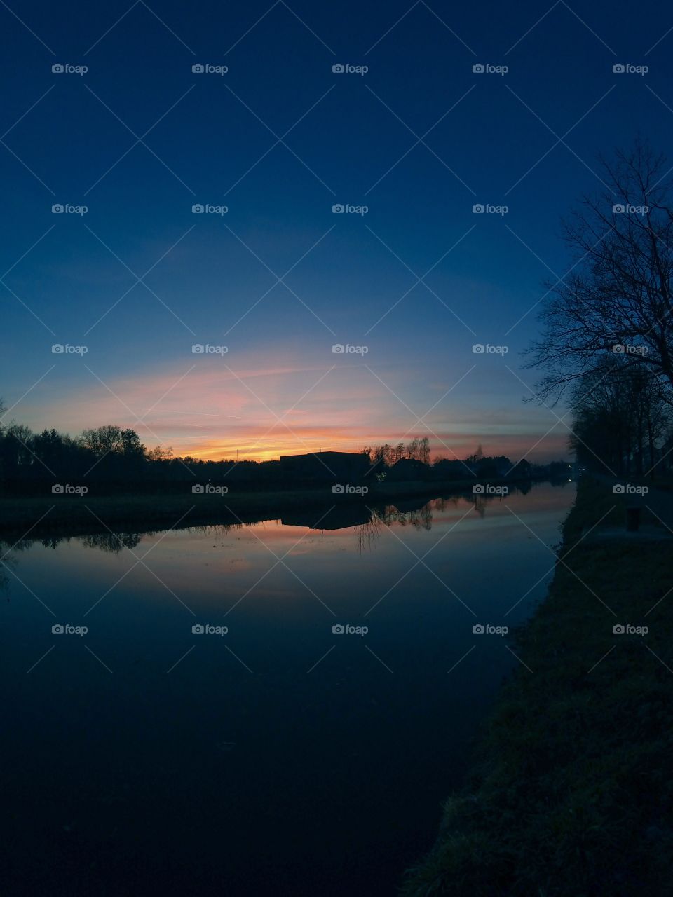 Countryside sunrise showing the colorful sky reflected in the water of the river 