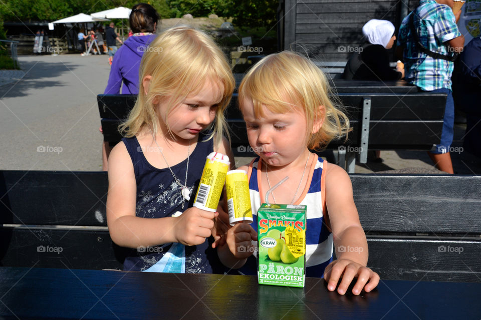 Two young sisters age five and two eating ice cream at Copenhagen Zoo in the summer.