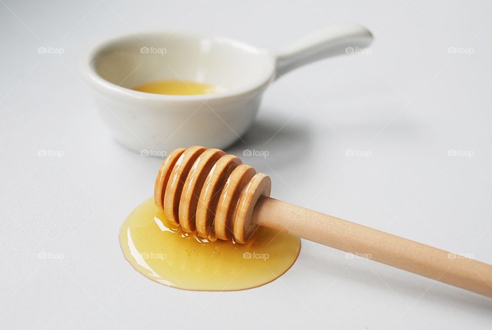 Honey on wooden honey stick with white background 