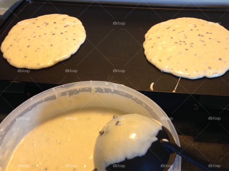 Two ladles of batter have been poured on the griddle.