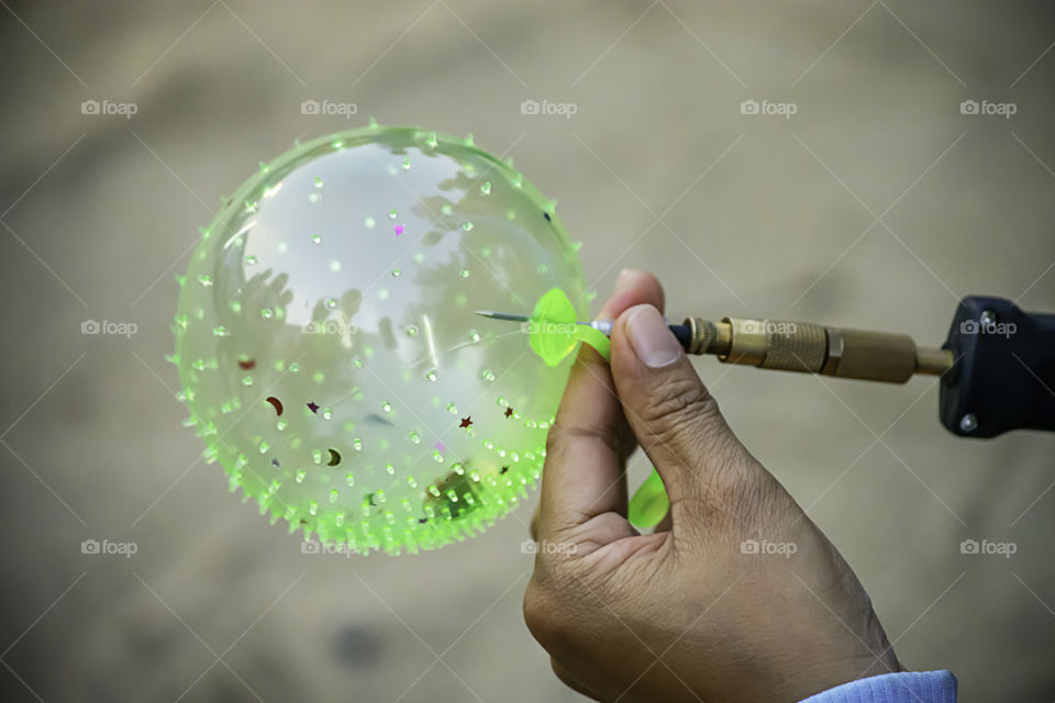 Hand holding a balloon and inflate with a needle.