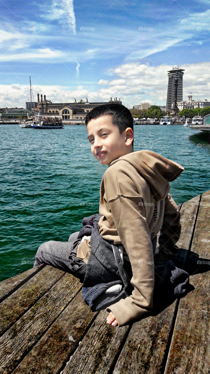 Boy sitting on pier over sea