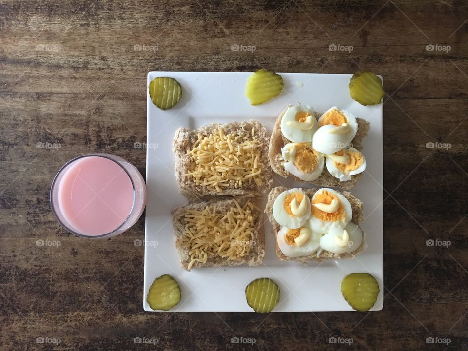 A nice lunch with boiled eggs, pickles, grated cheese and sandwich sauce. 