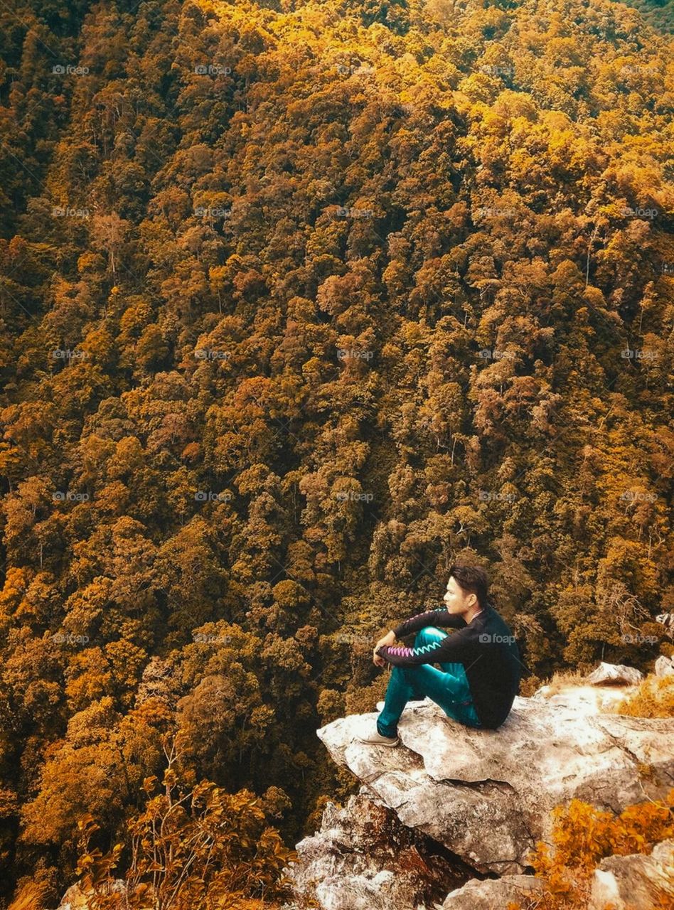 Man sitting on rock during autumn season