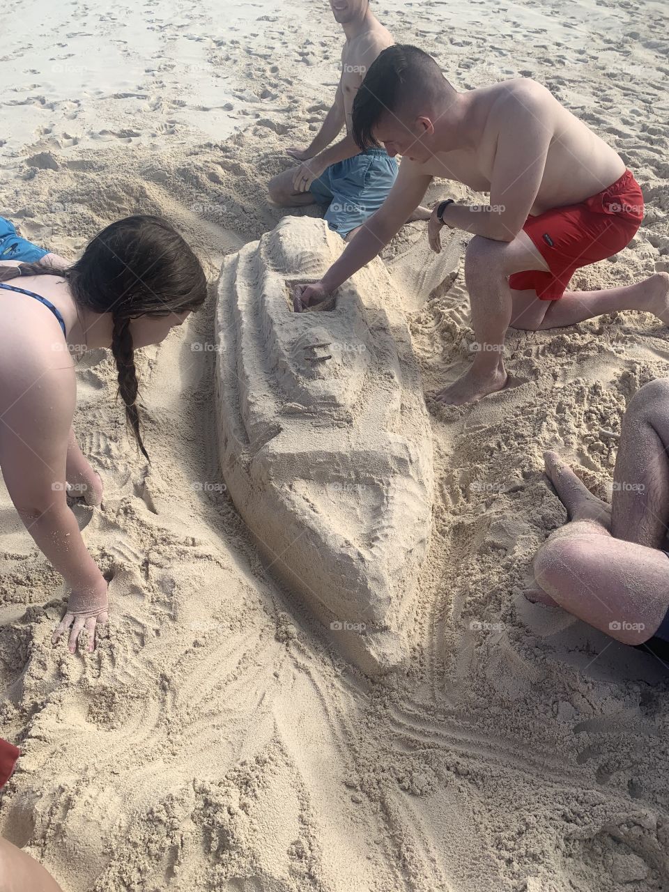 People on the Beach playing with sand making a boat