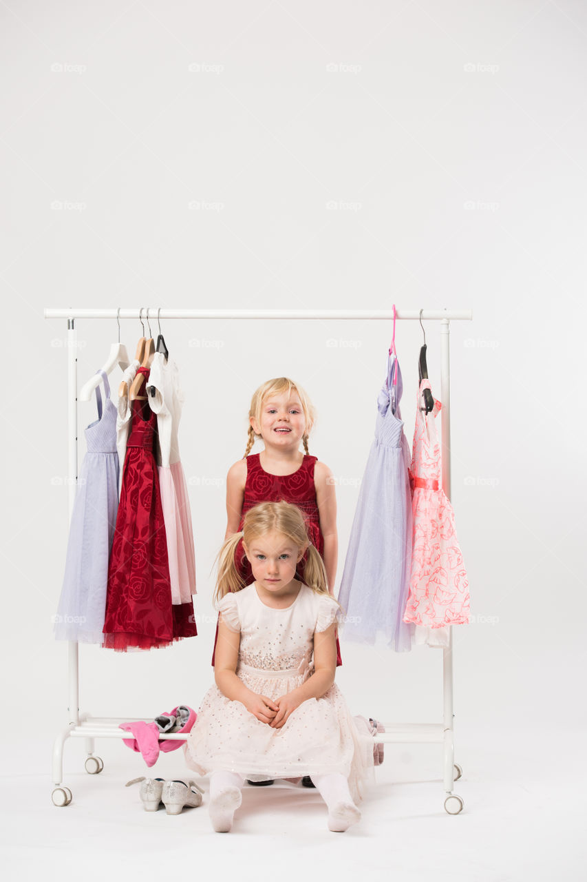Two cute sisters is posing and playing with clothes and having fun.