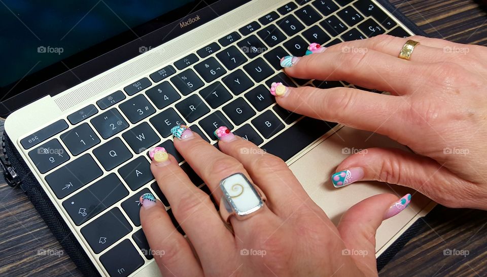 Fancy nails working on a Macbook