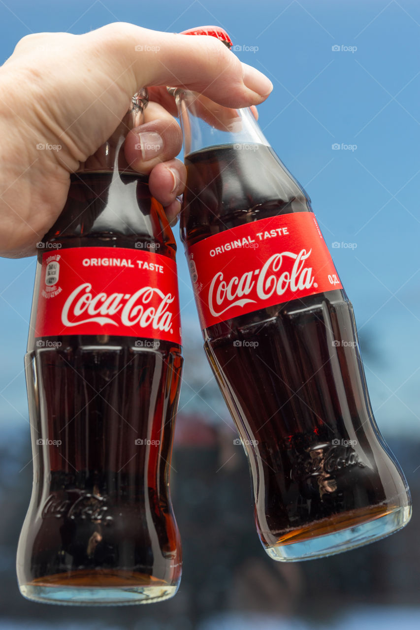 two bottles of Coke in a hand