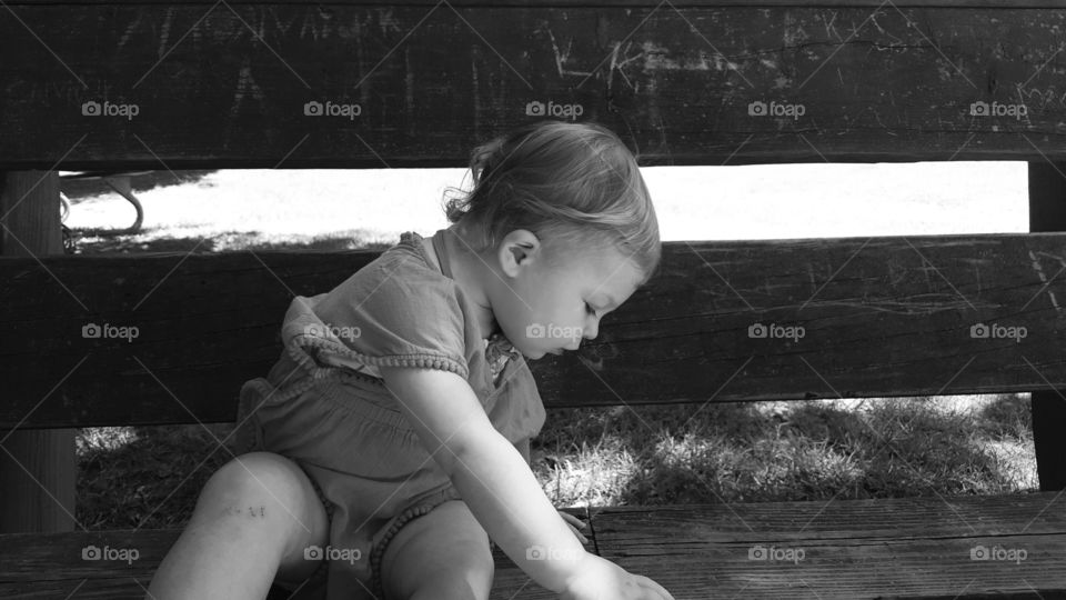 Close-up of cute girl sitting against wooden fence