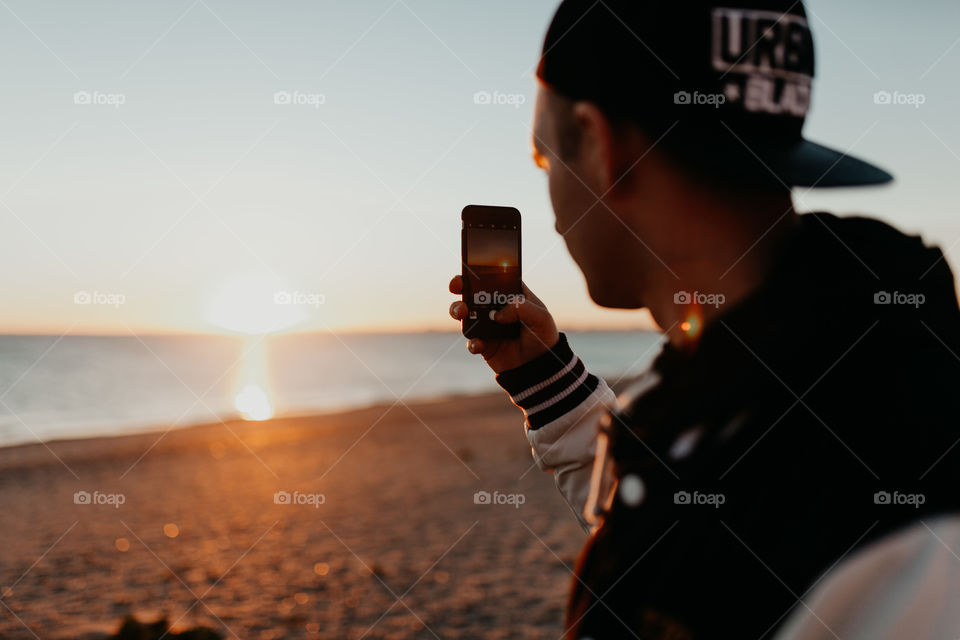 Young man making photo of sunset