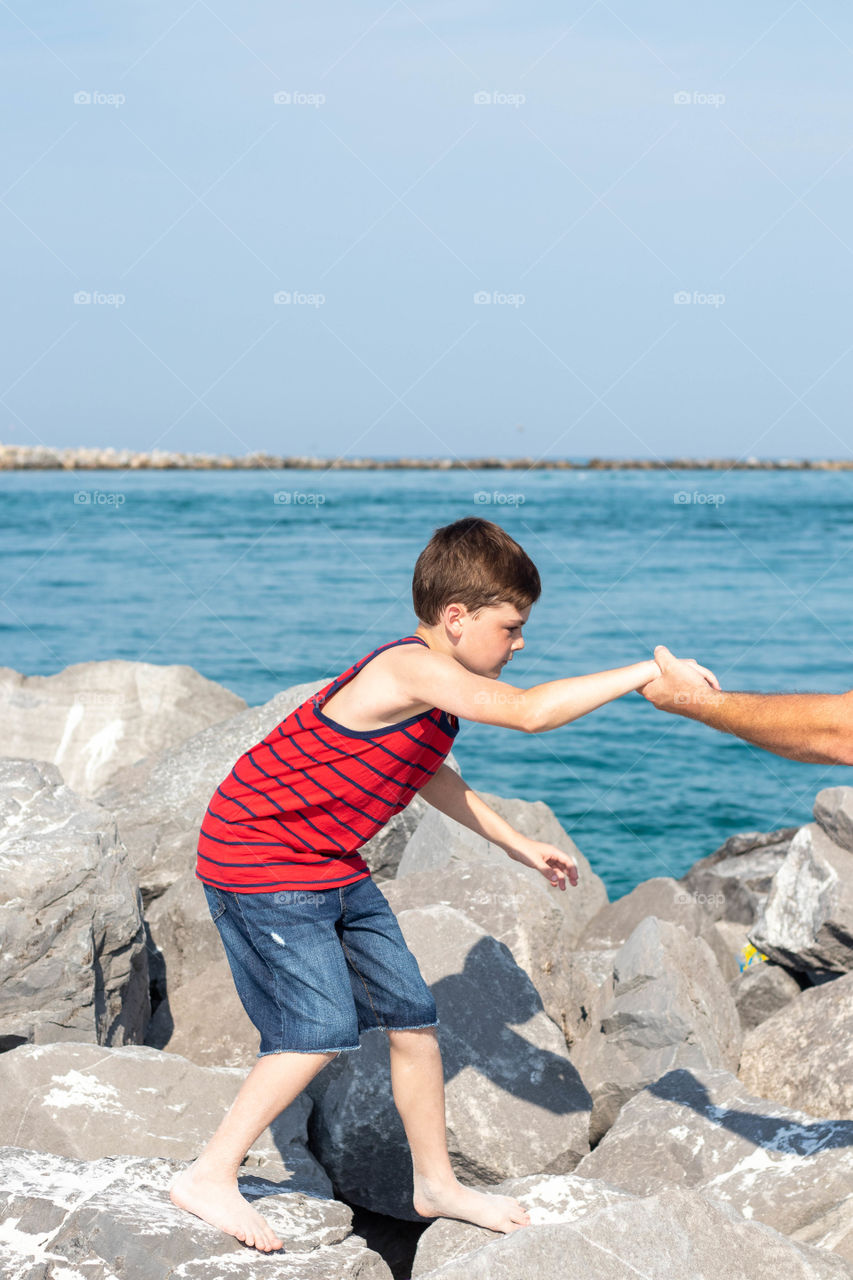 Boy getting help climbing rocks