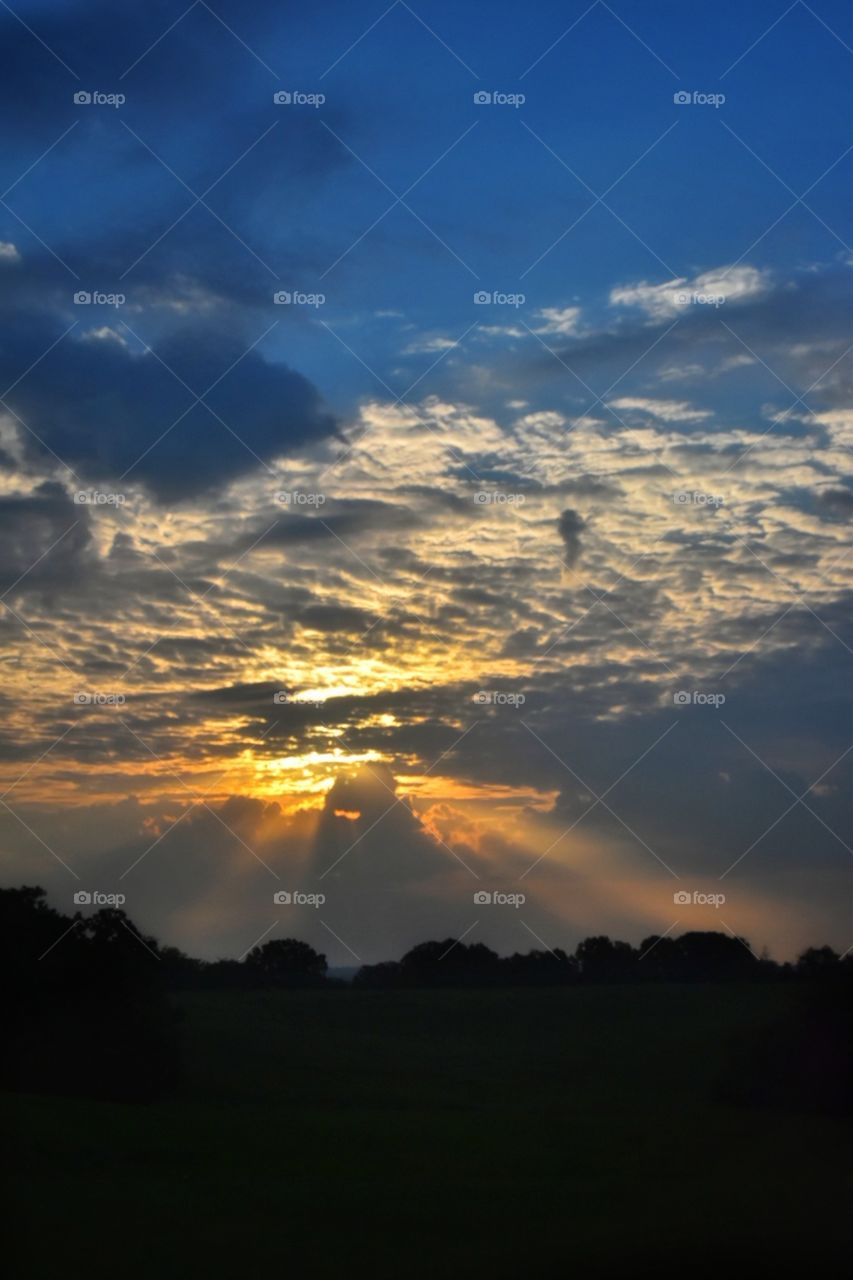 The rays from the setting sun glistening through the clouds 