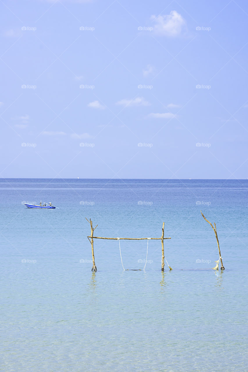 Swing chairs made from wood and fishing boats in the sea Background sky and cloud at Koh Kood, Trat in Thailand.