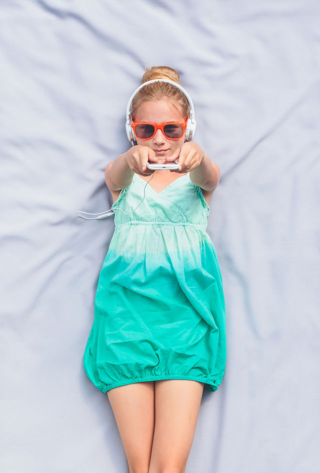 Teenage girl in headphones lying on bed