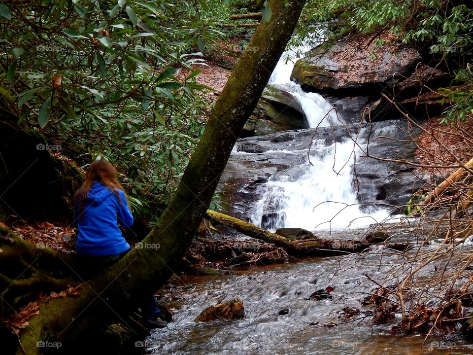 girl setting on log admiring a waterfall in Georgia's Chattahoochee national forest