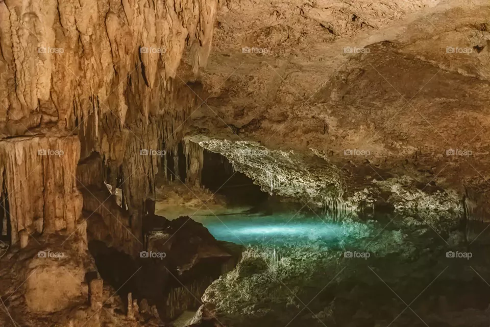 underground cenote with stalactites and stalagmites surrounded by crystal clear waters