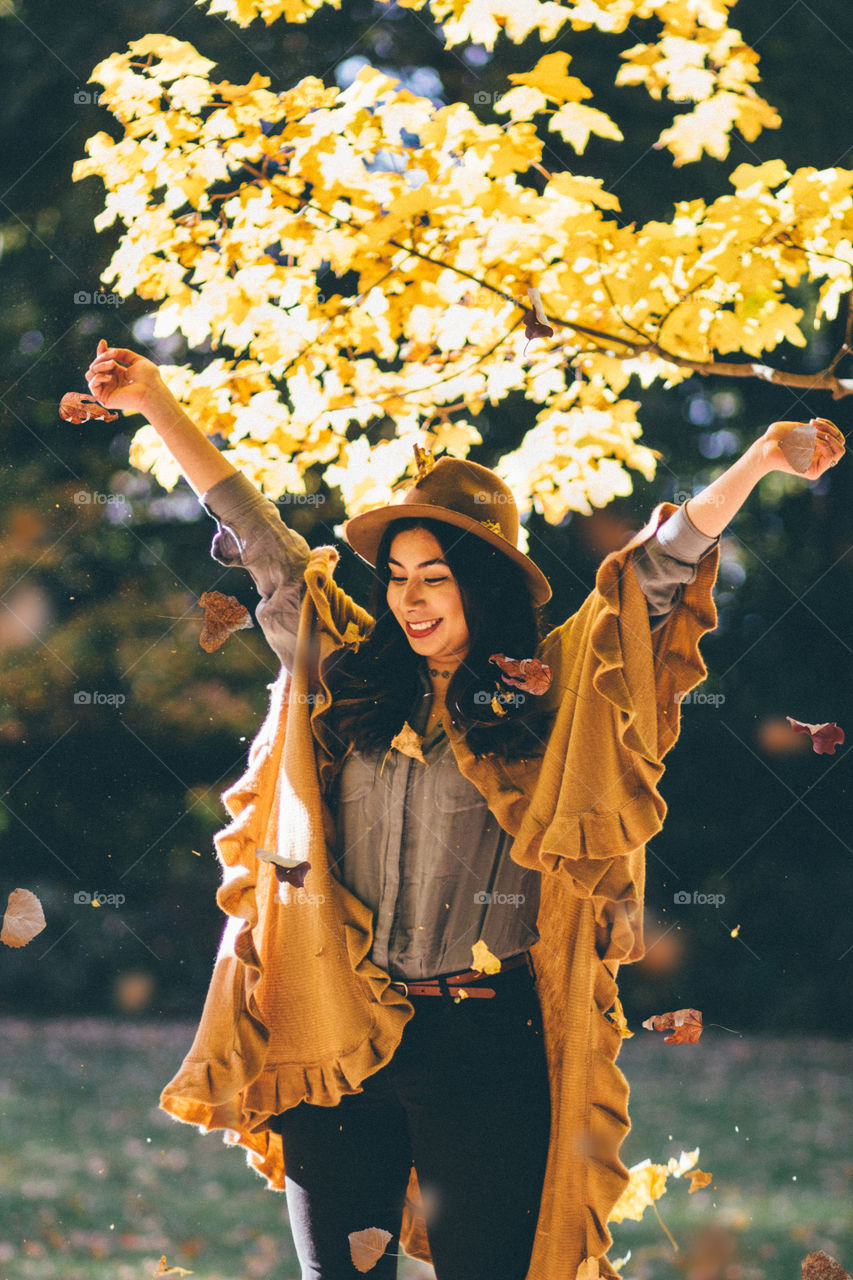 Happy woman standing near autumn tree