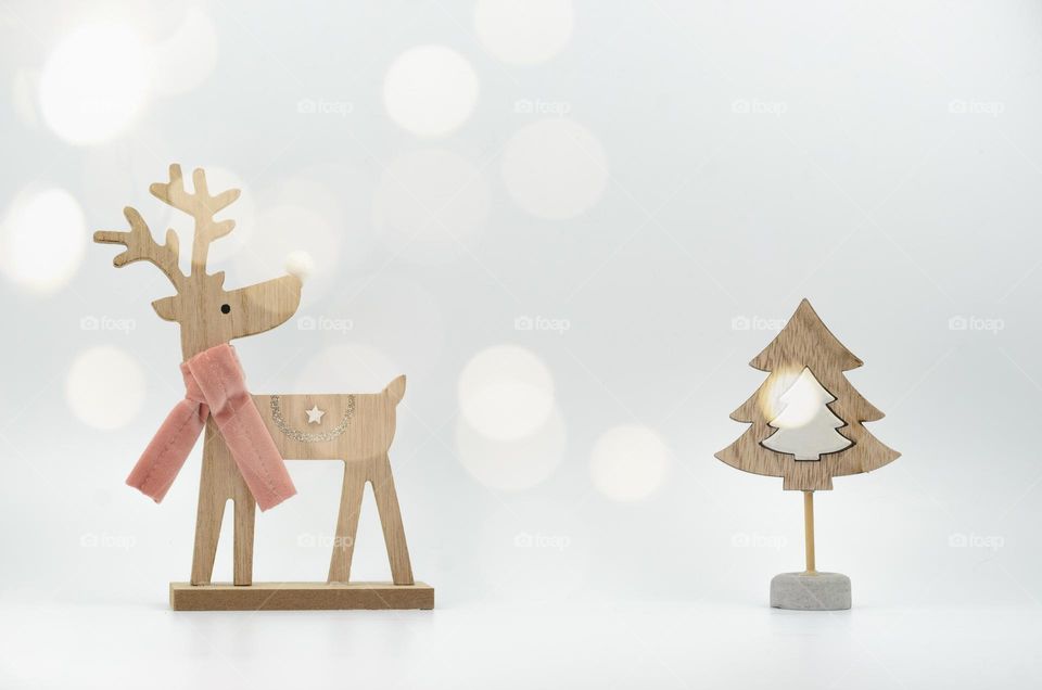 Minimalistic wooden Christmas decorations in the form of a deer and a fir tree on a white background. Christmas card. Bokeh.