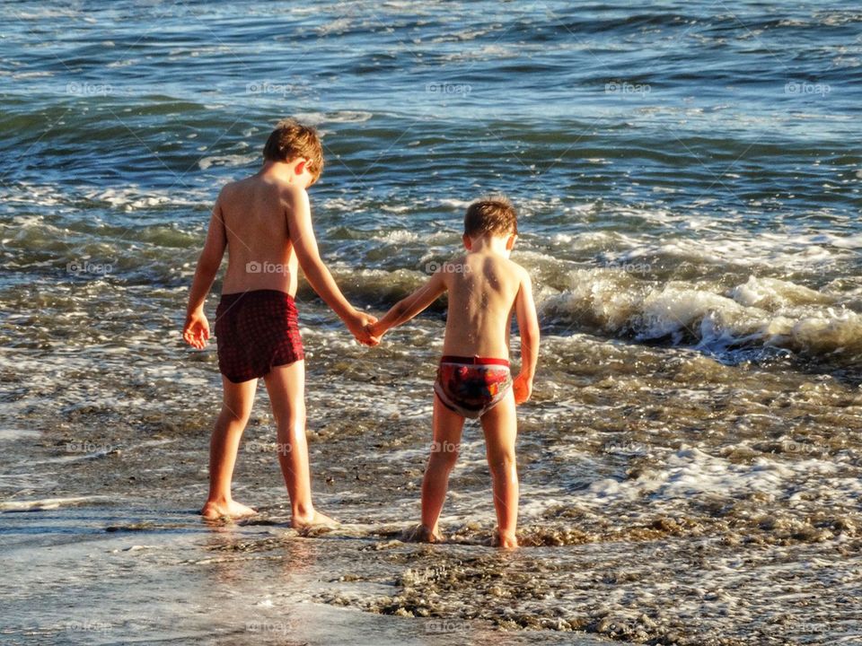 Brothers Holding Hands. Boys Playing In Ocean Waves