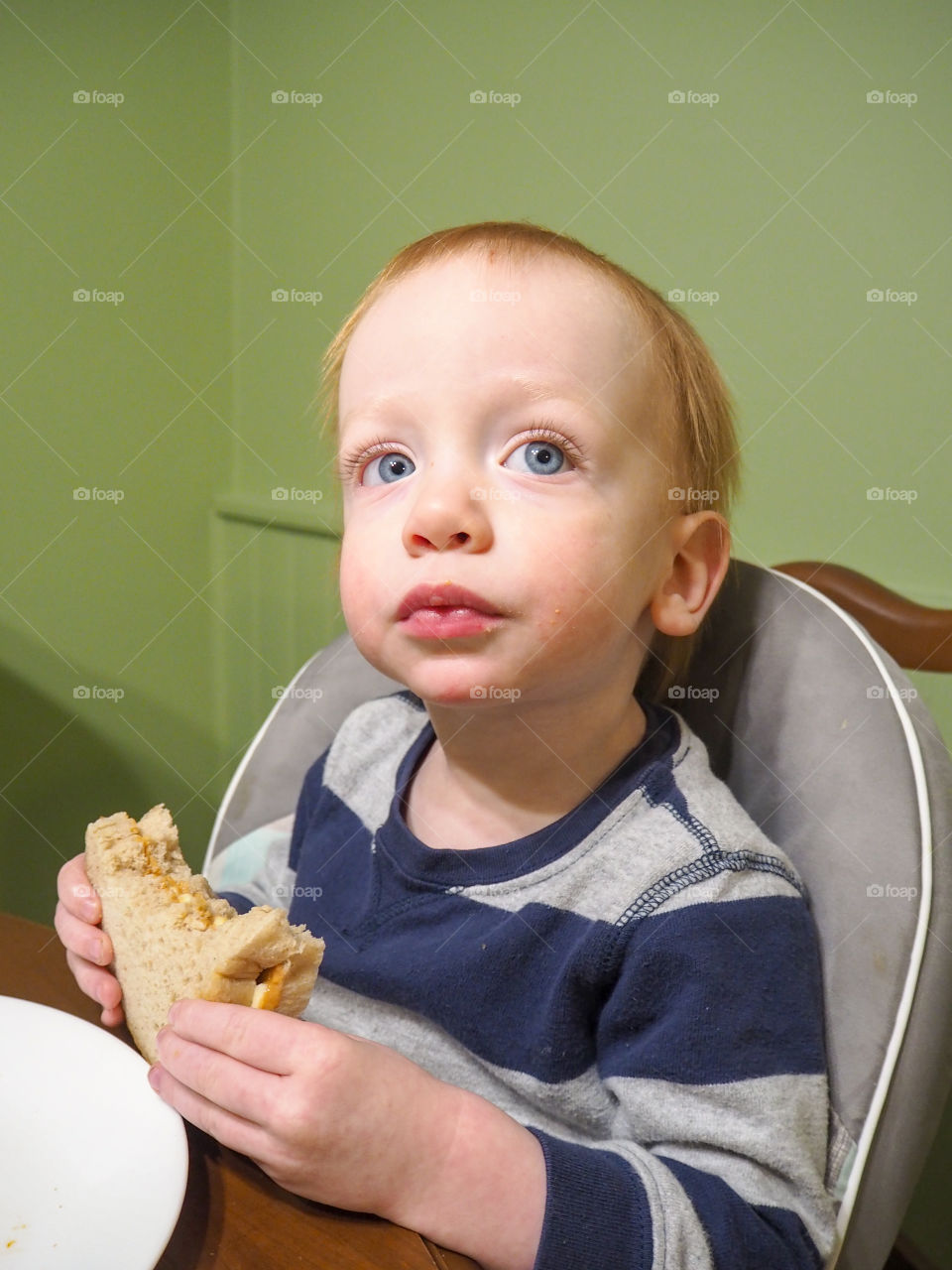 Toddler boy enjoying a peanut butter and banana sandwich