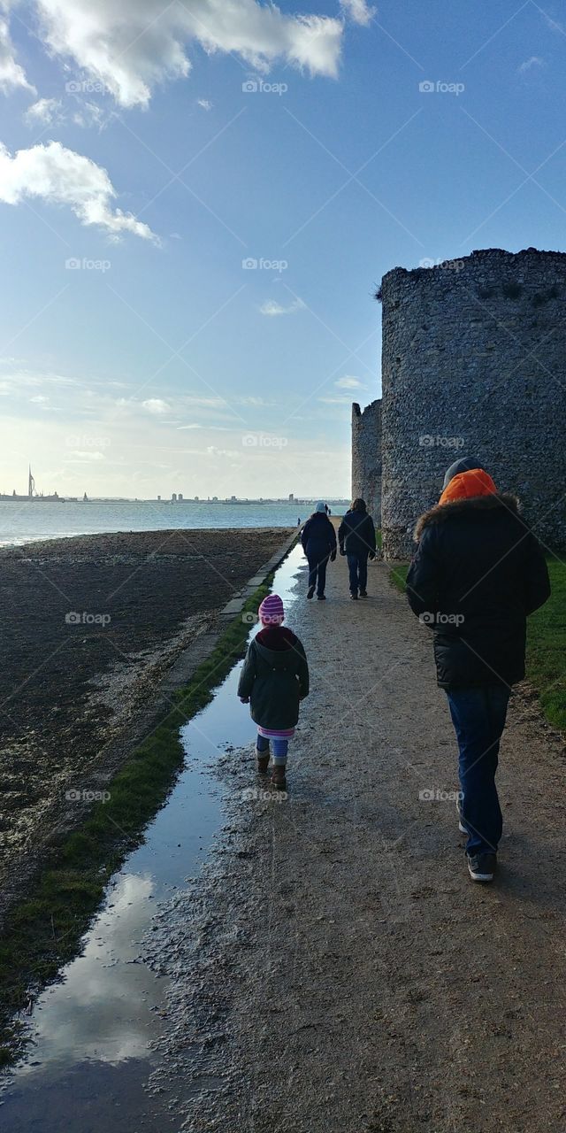 little girls walking on path between castle and shore in winter