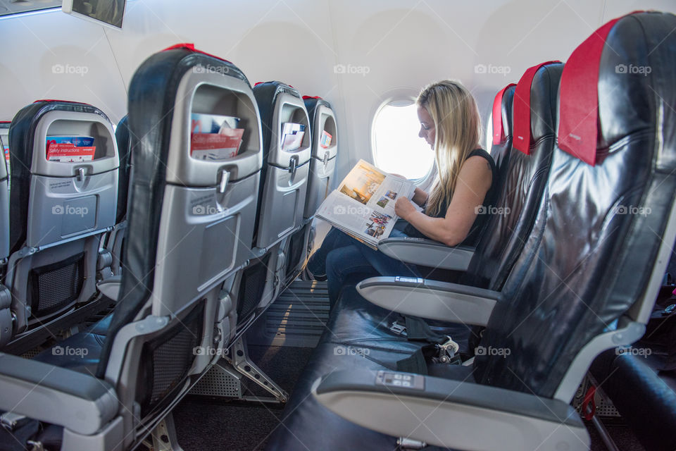 Woman reading the Tax Free catalog on a airplane.