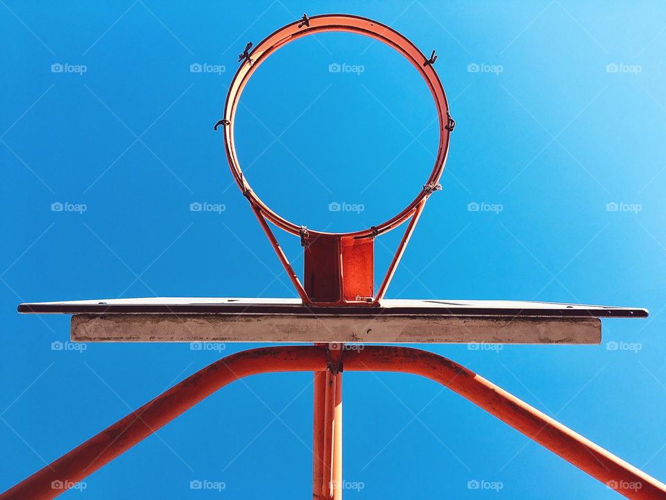 Basketball hoop against clear blue sky directly from below 