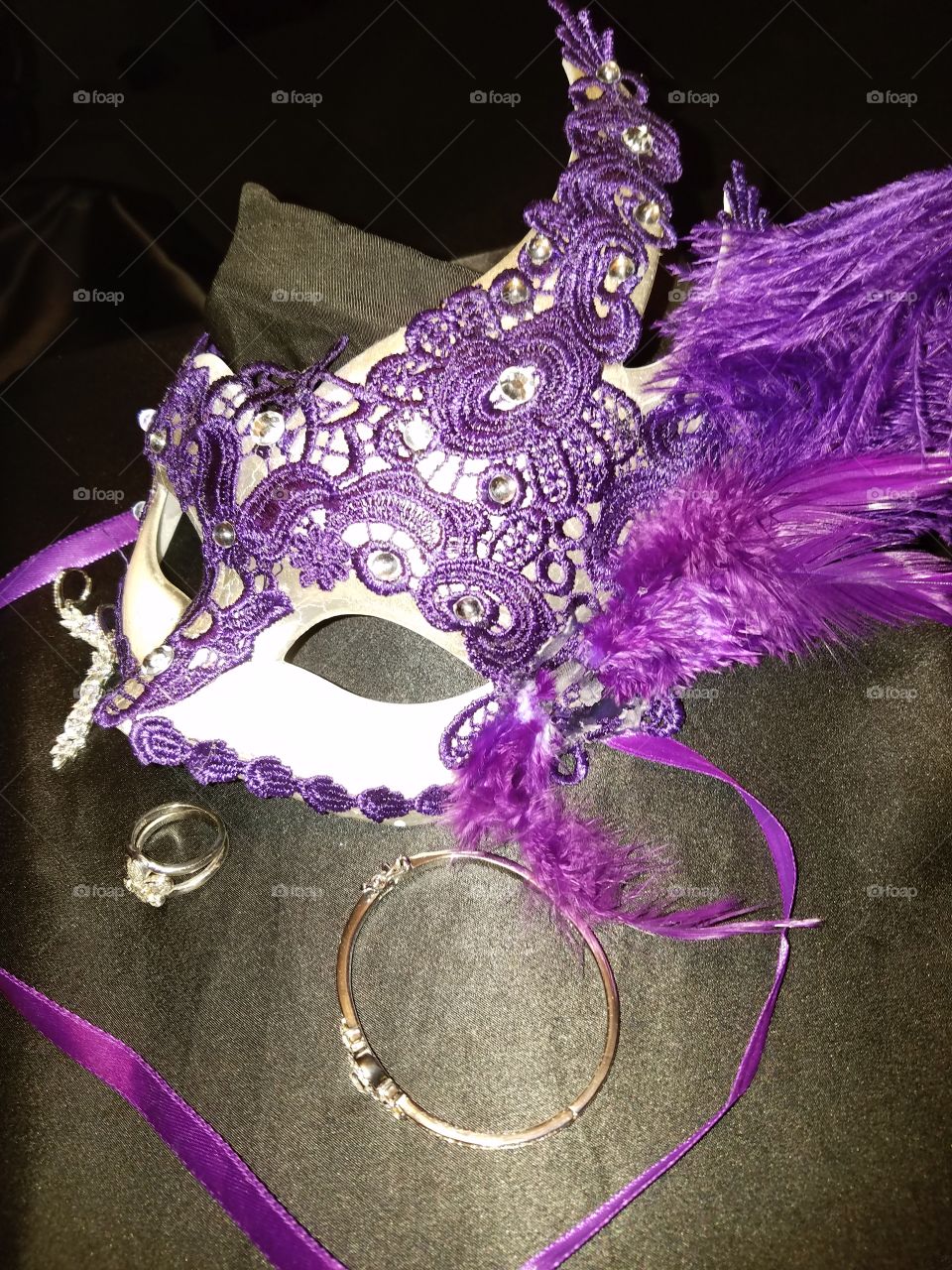 purple lace,feathers and satin ribbons Mardi Gras mask. diamond earrings fleur de lis ring and diamond bracelet