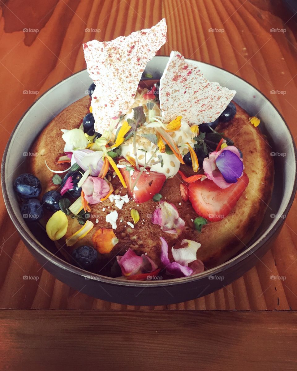 Colorful breakfast hotcake with fruit, white chocolate and edible flowers